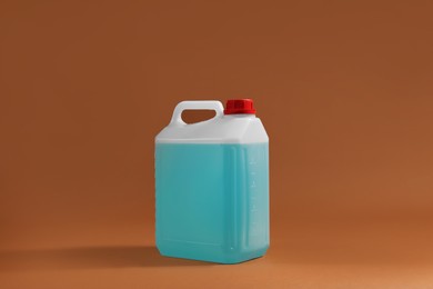 Photo of Plastic canister with blue liquid on brown background