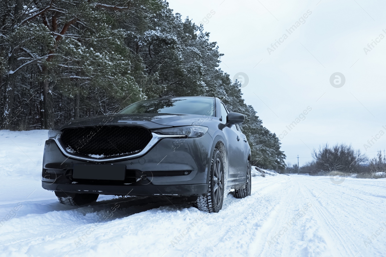 Photo of Snowy country road with car on winter day