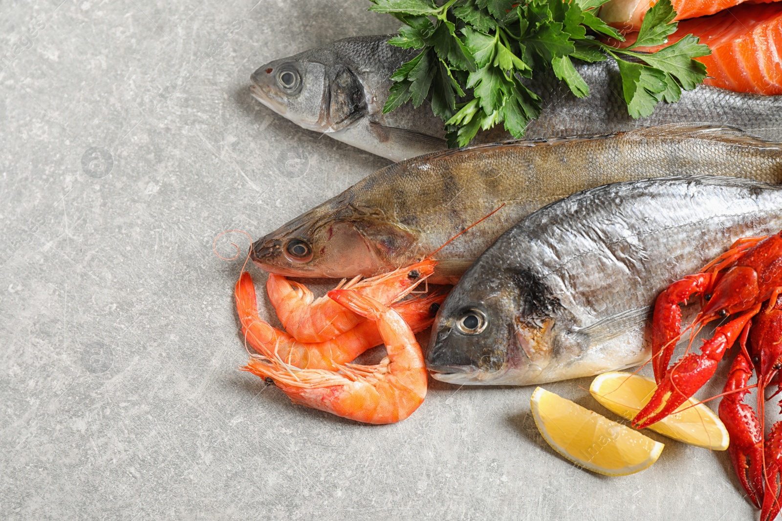 Photo of Fresh raw fish and different seafood on light grey table