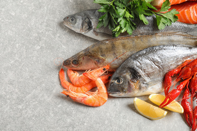 Photo of Fresh raw fish and different seafood on light grey table