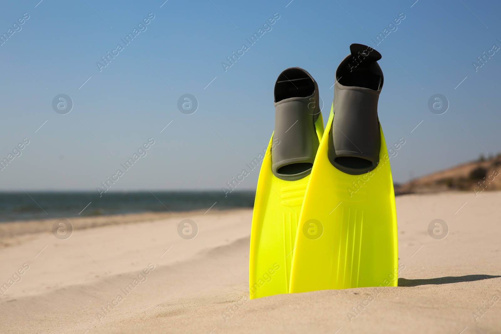 Photo of Pair of bright flippers on sandy beach, space for text