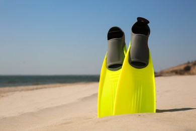 Photo of Pair of bright flippers on sandy beach, space for text
