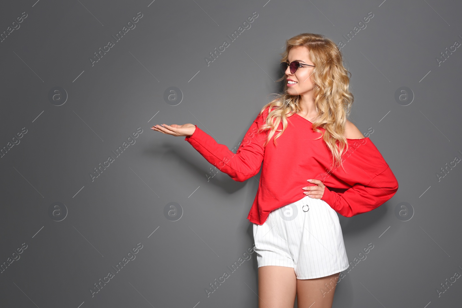 Photo of Stylish young woman with sunglasses posing on grey background