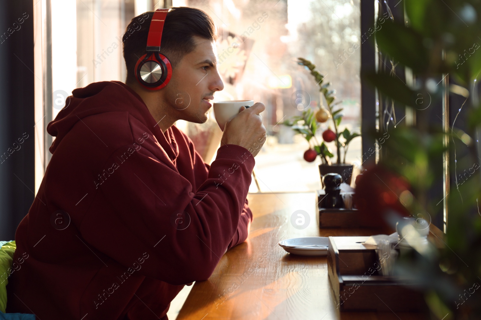 Photo of Man listening to audiobook at table in cafe