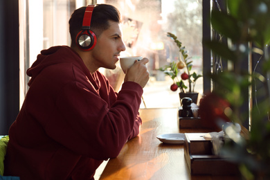 Photo of Man listening to audiobook at table in cafe