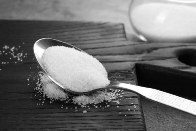 Photo of Spoon with granulated sugar on grey table, closeup