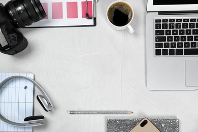 Flat lay composition with laptop, camera and color palette on grey stone table, space for text. Designer's workplace