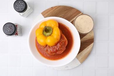 Photo of Delicious stuffed bell pepper served on white tiled table, flat lay