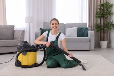 Female worker cleaning carpet with vacuum in living room