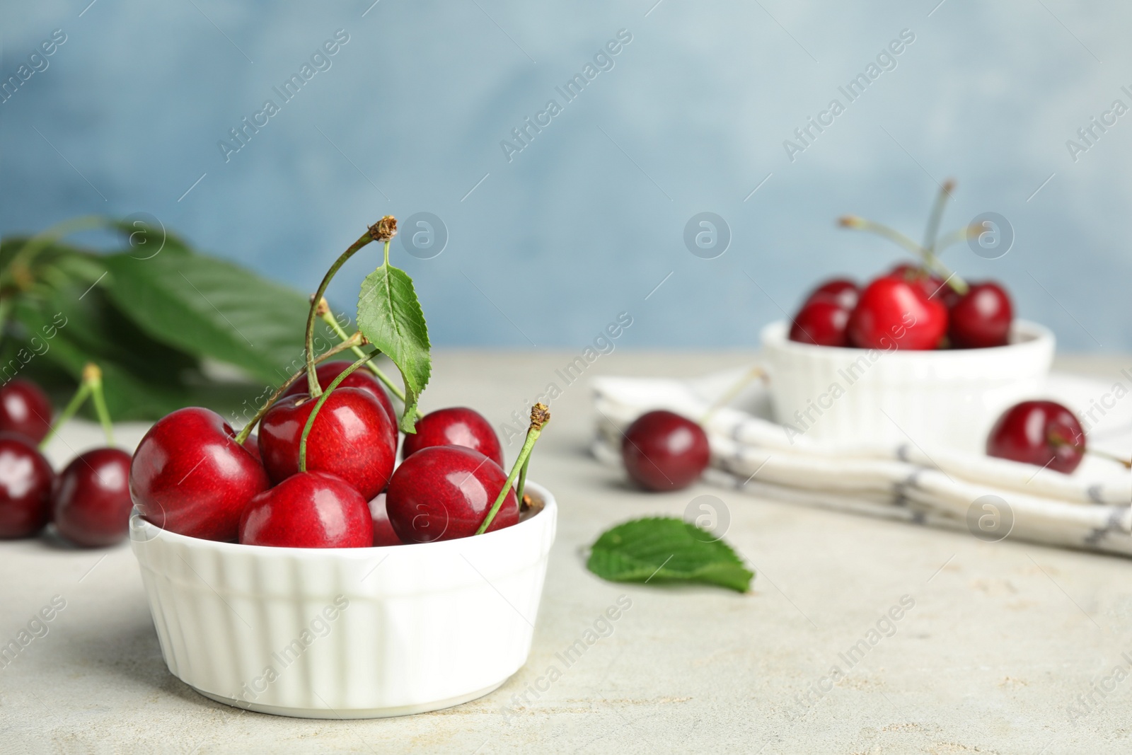 Photo of Bowl with ripe sweet cherries on light table. Space for text