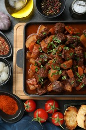 Photo of Delicious beef stew and ingredients on grey table, flat lay