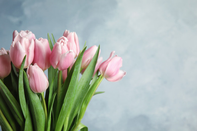 Photo of Beautiful pink spring tulips on light blue background, closeup. Space for text