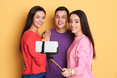 Photo of Young happy friends taking selfie against color background