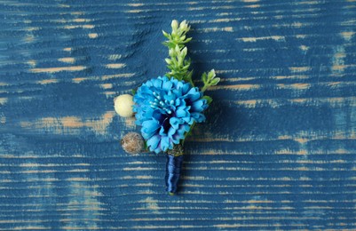 Photo of Stylish boutonniere on blue wooden table, top view