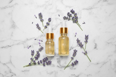 Photo of Flat lay composition with lavender flowers and natural essential oil on white marble table