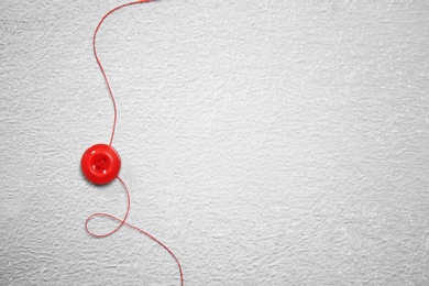 Photo of Thread and button on light background. Tailoring accessories