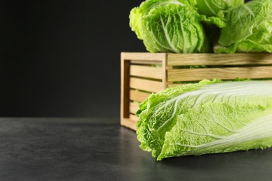 Photo of Fresh ripe Chinese cabbages and wooden crate on grey table, space for text