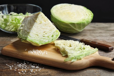 Photo of Cutting board with chopped and sliced cabbage on table