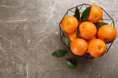 Delicious ripe oranges in fruit bowl on grey marble table, flat lay. Space for text