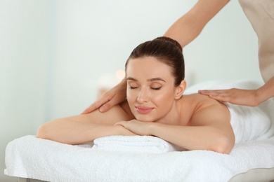 Photo of Beautiful young woman enjoying massage in spa salon