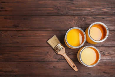 Photo of Flat lay composition with paint cans and brush on wooden background. Space for text