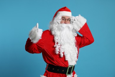 Photo of Merry Christmas. Santa Claus showing thumbs up on light blue background