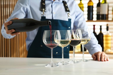 Photo of Bartender pouring wine into glass at counter in restaurant, closeup