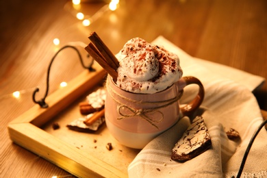 Photo of Tasty hot drink with whipped cream and cookies on  wooden table, closeup