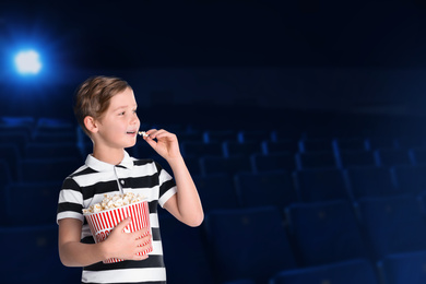 Image of Cute boy with popcorn bucket in cinema, space for text