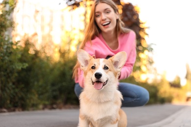 Photo of Young woman with adorable Pembroke Welsh Corgi dog outdoors