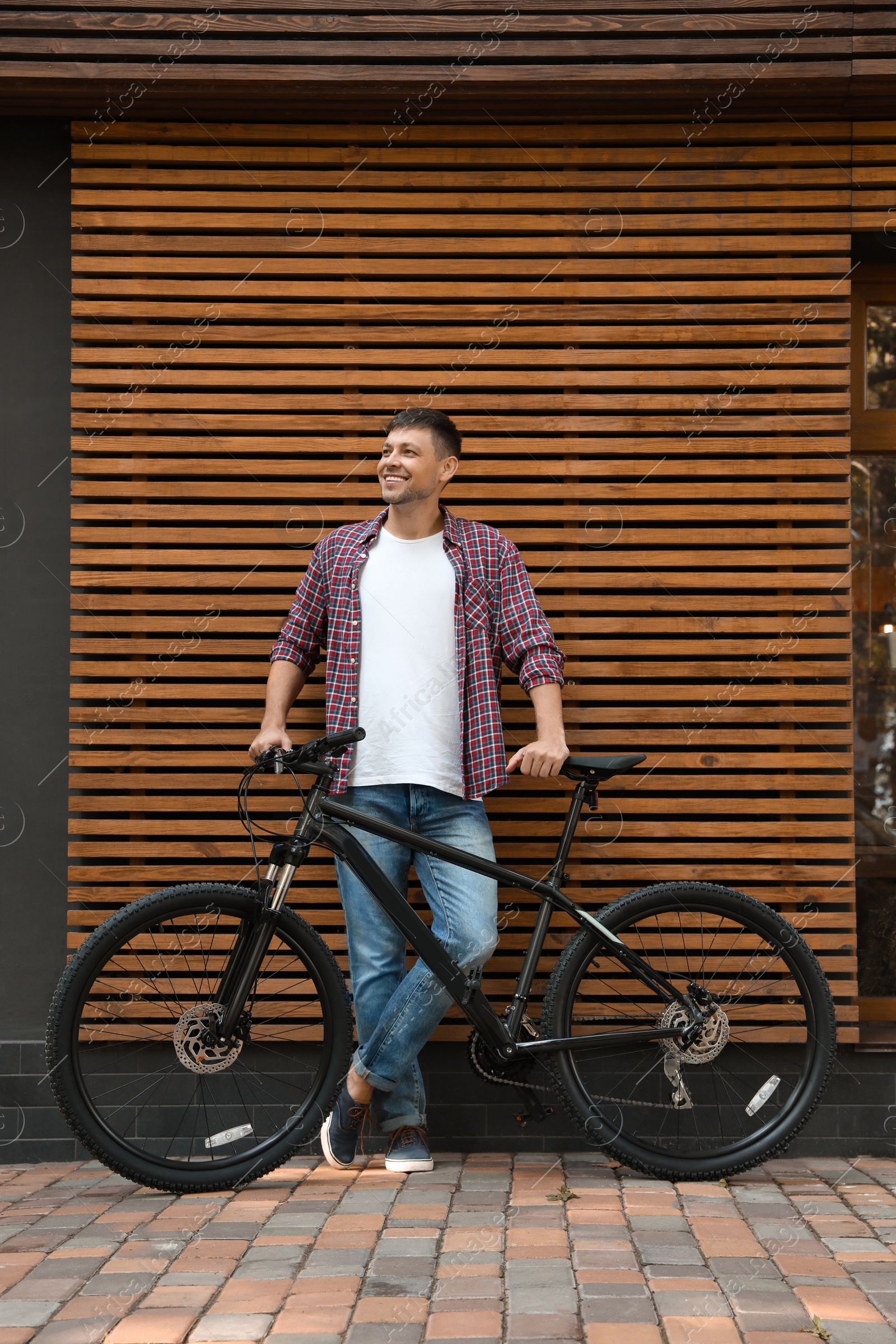 Photo of Handsome man with modern bicycle near building outdoors