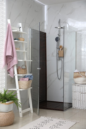 Photo of Bathroom interior with shower stall and shelving unit. Idea for design