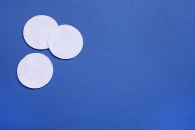 Photo of Cotton pads on blue background, flat lay. Space for text