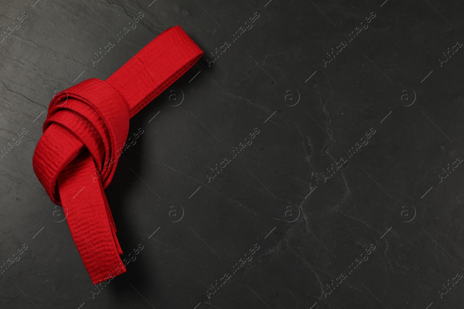 Photo of Red karate belt on gray background, top view. Space for text