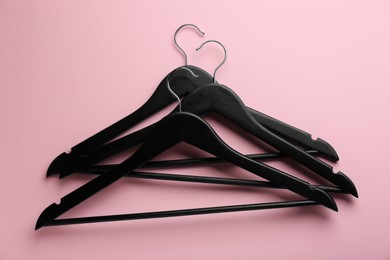 Photo of Black hangers on pink background, top view