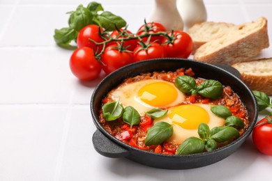 Photo of Delicious Shakshuka served on white tiled table, space for text