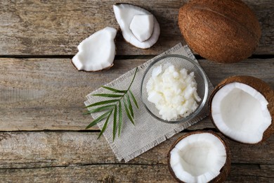 Photo of Organic coconut cooking oil, fresh fruits and leaf on wooden table, flat lay. Space for text