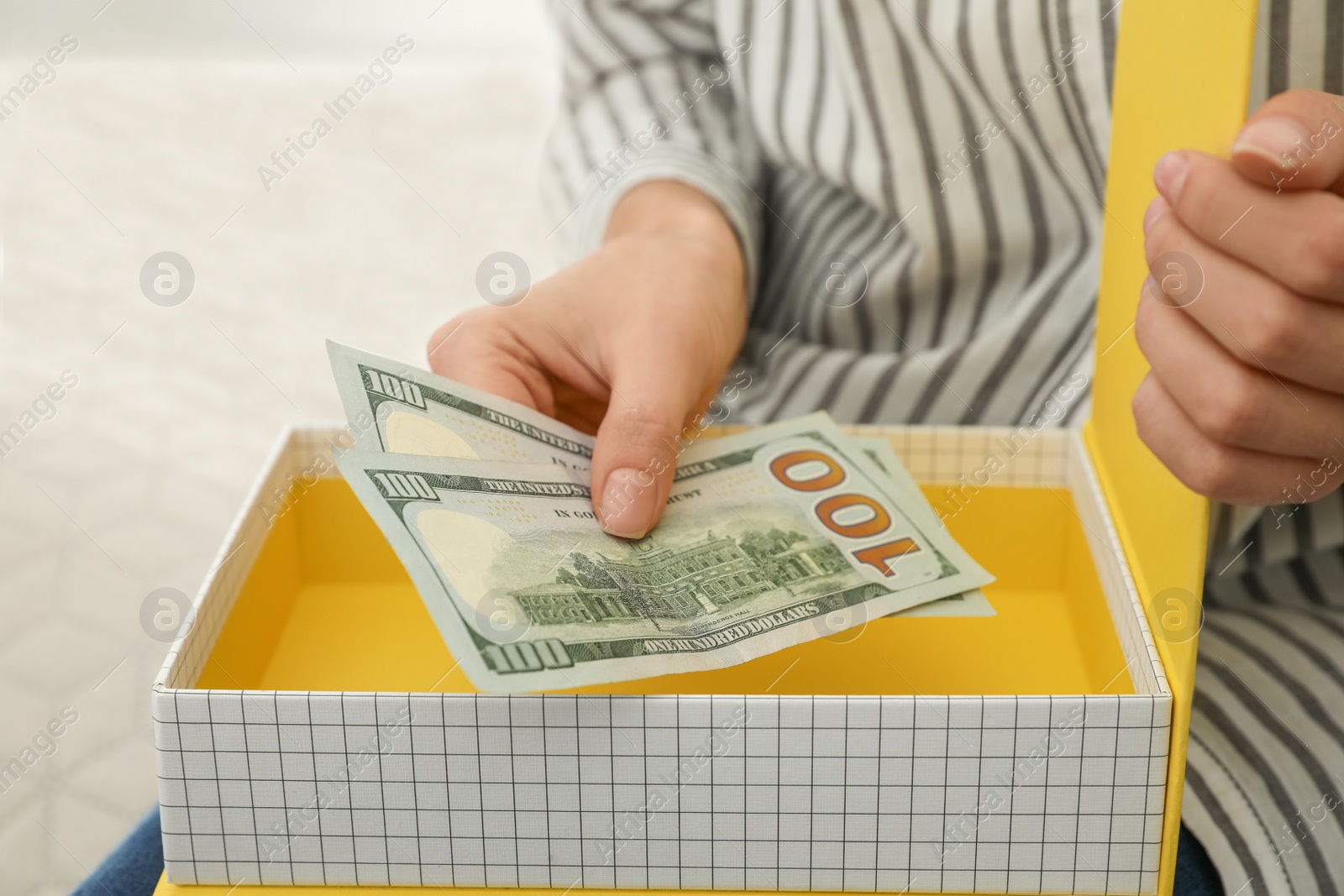Photo of Woman hiding dollar banknotes in box at home, closeup. Money savings