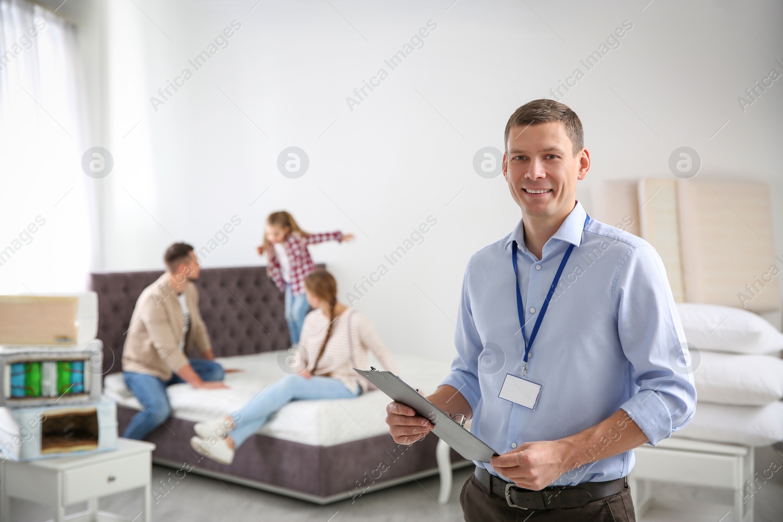 Photo of Happy salesman and his clients in mattress store
