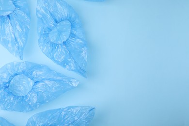 Photo of Medical shoe covers on light blue background, flat lay. Space for text