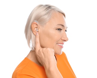 Photo of Mature woman adjusting hearing aid on white background