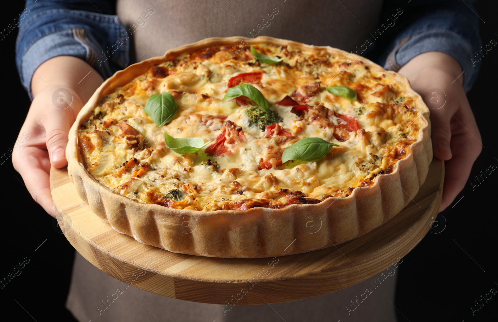 Woman holding board with tasty quiche on black background, closeup Photo of Woman holding board with tasty quiche on black background, closeup