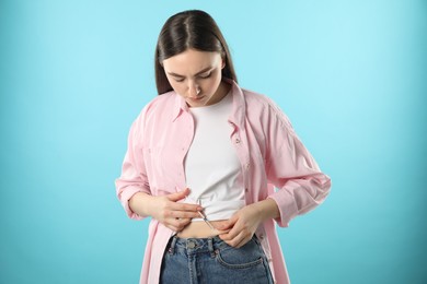 Photo of Diabetes. Woman making insulin injection into her belly on light blue background