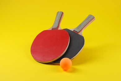 Photo of Ping pong ball and rackets on yellow background