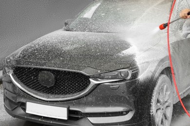 Photo of Man washing auto with high pressure water jet at car wash, closeup