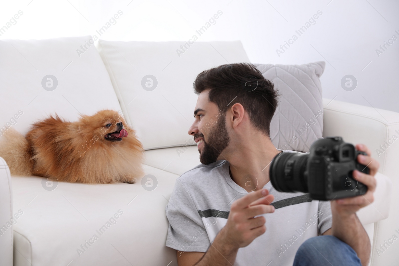 Photo of Professional animal photographer taking selfie with beautiful Pomeranian spitz dog indoors