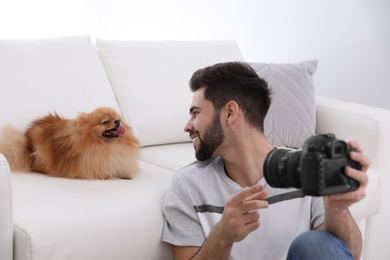 Photo of Professional animal photographer taking selfie with beautiful Pomeranian spitz dog indoors