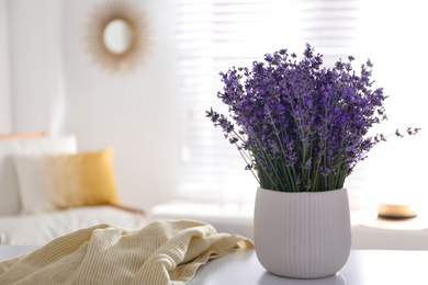 Photo of Beautiful lavender flowers and yellow shirt on white table indoors. Space for text