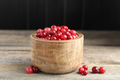 Photo of Ripe cranberries in bowl on wooden table