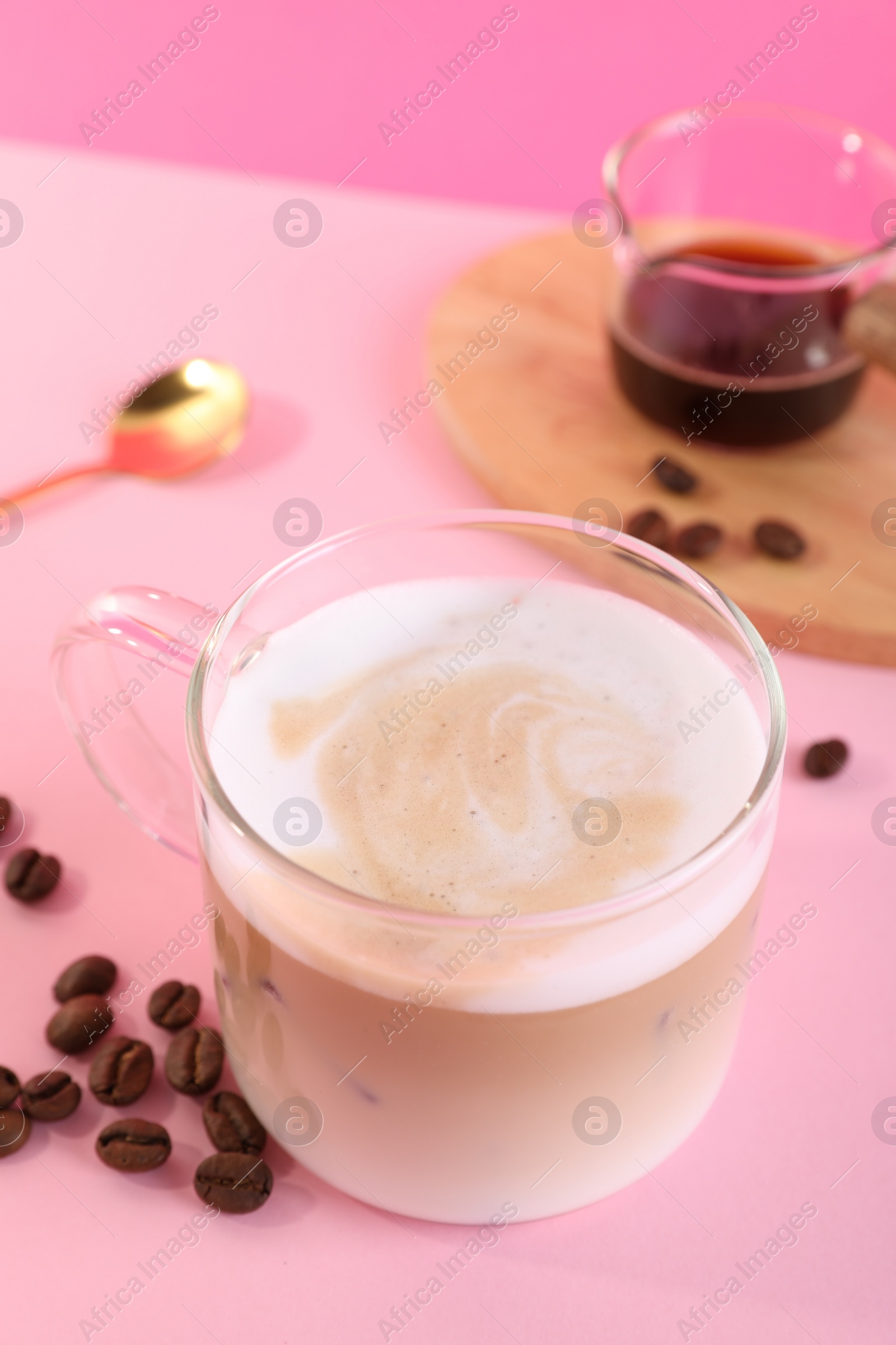 Photo of Cup of fresh coffee and beans on pink table, closeup